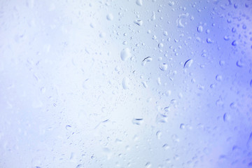 Water drops on glass, rain drop background defocused on blue surface.