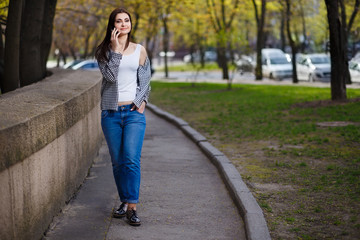 Young pretty stylish woman talking on smart phone in the street