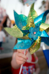 A child is playing with a pinwheel on the 4th of July at a crowded beach.