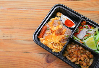 fried rice with shrimp paste include mango, egg, pork, onion, vegetable in box black / Thai style food on a wood table background