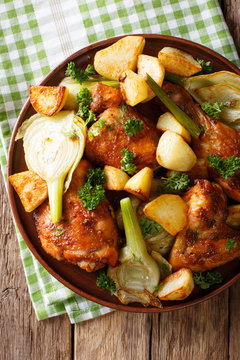 Pieces of chicken baked with fennel and potatoes close-up. Vertical top view