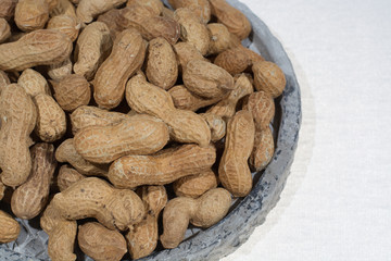 Peanuts in shell on the grey pate, white backgound, close up, copy space