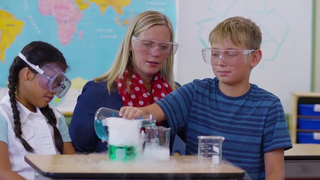 Teacher doing science experiment with students in school classroom