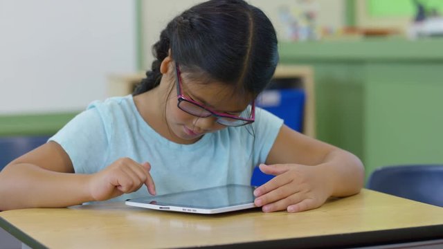 Young Girl In School Classroom Using Digital Tablet