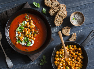 Tomato soup with spicy fried chickpeas on a dark wooden table, top view. Healthy vegetarian food...