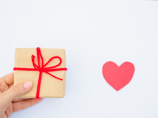 Hands holding beautiful gift box with red heart, female giving gift, Christmas holidays and greeting season concept, shallow dof