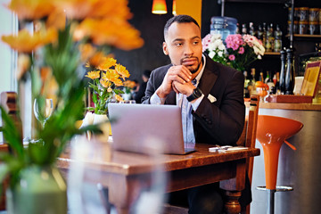 Thoughtful male in a cafe using laptop.