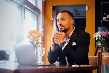 Portrait of a man using a laptop in a restaurant.