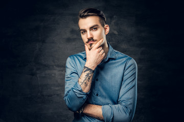 Thoughtful male with tattooed arm.