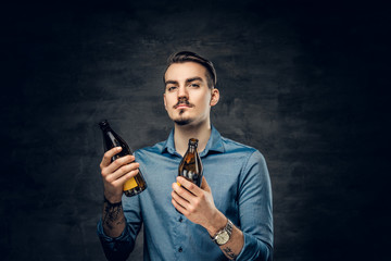 A man holds two craft bottled beers.