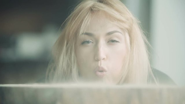 Female Carpenter Blowing Off Sawdust On Tree Stump