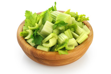 Fresh sliced celery in a wooden bowl isolated on white background.