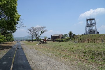 Obraz premium 世界文化遺産の万田坑 熊本県荒尾市の旧三池炭鉱 三池港まで敷かれていた石炭搬出用鉄道の廃線路址から見た竪坑櫓