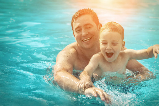 Father And Son Funny In  Water Pool Under Sun Light At Summer Da