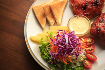 Chickens fried steak with vegetables salad on white dish and wooden background