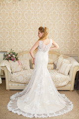 Pretty young Bride.blonde-haired woman with wedding hair-style with a long tail. Boudoir morning of the bride. View from the back