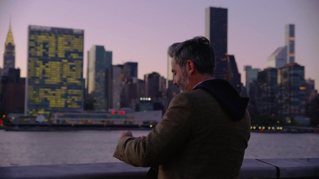 Man in New York City taking photos of city with cell phone