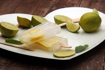 Healthy lime mint popsicles with fresh lime slices on wooden background