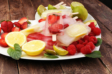 Healthy raspberry, lemon, lime, strawberry popsicles with fresh slices on wooden background