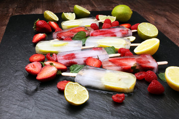 Healthy raspberry, lemon, lime, strawberry popsicles with fresh slices on wooden background