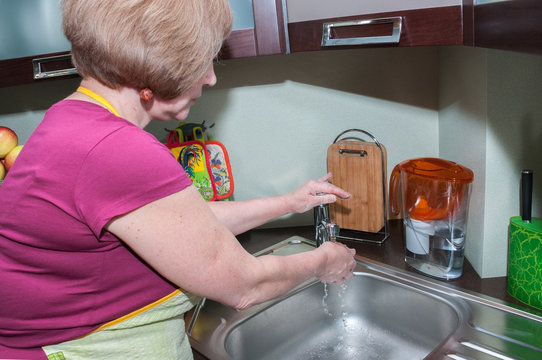 woman is washing her hands in the kitchen.