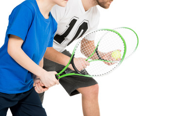 partial view of father and son with tennis racquets isolated on white