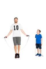 active man jumping with skipping rope with son standing near by isolated on white