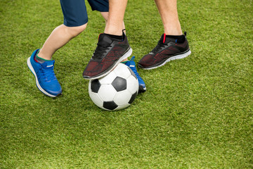 partial view of father and son playing soccer on grass