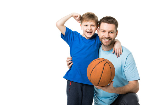 Smiling father and child ready to play basketball. Boy showing his biceps isolated on white