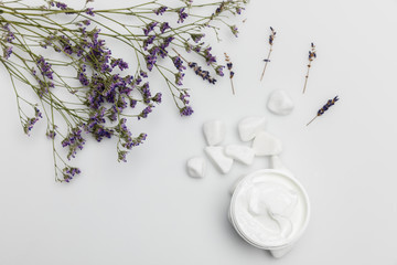 Top view of organic cream in container and dried lavender isolated on white