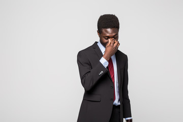 Obraz na płótnie Canvas Frustrated young African man massaging nose and keeping eyes closed while standing against grey background