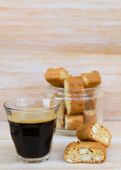 Homemade biscotti cantuccini or cantucci, Italian almond sweets biscuits (cookies) and glass of espresso coffee on wooden table.