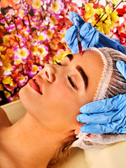 Obraz na płótnie Canvas Filler injection for female forehead face. Plastic aesthetic facial surgery in beauty clinic. Beauty woman giving injections. Doctor in medical gloves with syringe on spring flowers background.