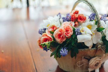 wooden basket with fresh flowers on wooden background. original gift
