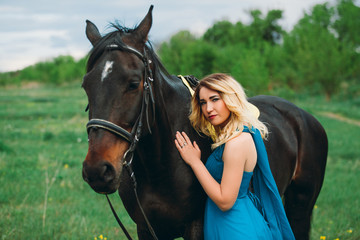 Obraz premium Girl in meadow with a horse on green grass
