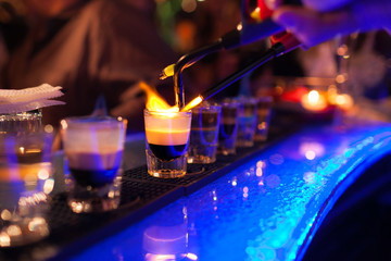 The bartender makes hot alcoholic cocktail and ignites bar. elite night club during party prepares...