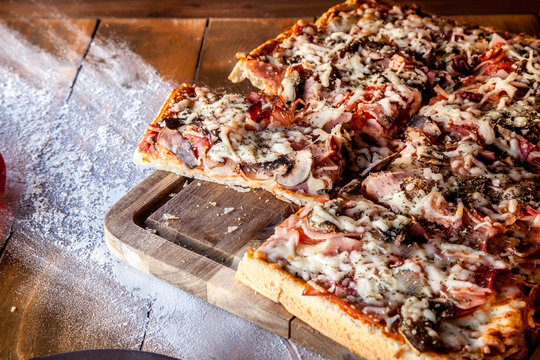 Rectangular ham and mushroom pizza served on wooden board