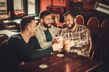 Cheerful old friends having fun and drinking draft beer in pub.