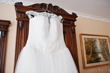 White wedding dress on hangers for bride at room.