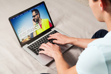 Man searching for car insurance on the internet with a laptop at home.