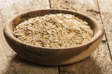 Plate with raw oatmeal on wooden table.