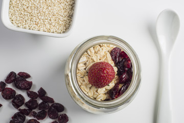 Healthy breakfast - Fresh homemade granola, berries and y yogurt in a glass jar on a white wooden background, selective focus