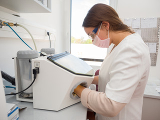 Female dental technician using a sandblasting machine
