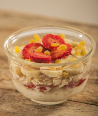 Oatmeal with banana, strawberry and glass of milk on brown wooden table
