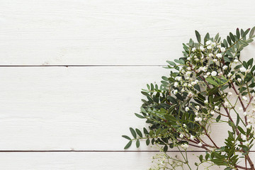 Bouquet of small white flowers and twigs on a white wooden background.