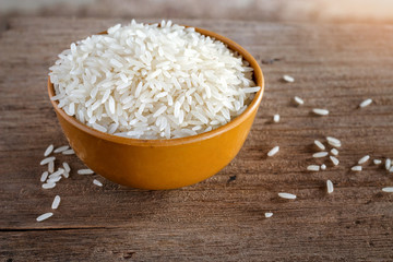 Uncooked dry rice in brown bowl on wooden table