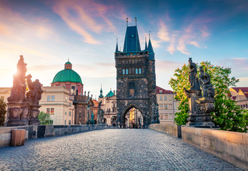 Fototapeta na wymiar Sunny spring scene on Charles bridge on Vltava river (Karluv Most) with statues and Saint Francis of Assisi Church.