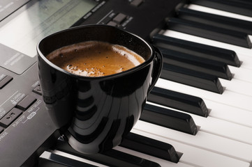Coffee cup on piano keyboard