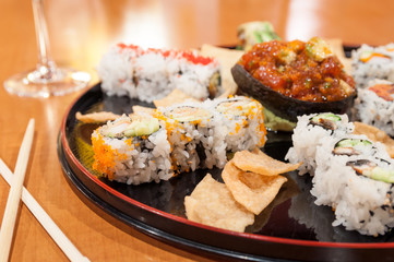 Large sushi platter served on a round dish with crisps and tuna tartare.