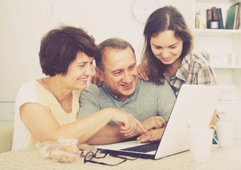 senior couple and daughter with laptop at home.